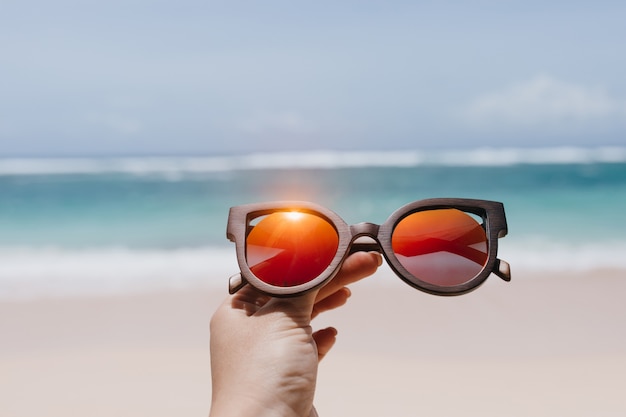 바다 위에 세련 된 여름 선글라스를 들고 여자입니다. 해변에서 안경 여성 손의 야외 사진.