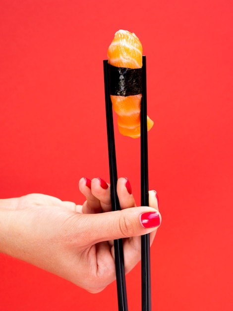 Woman holding a sushi on a red background