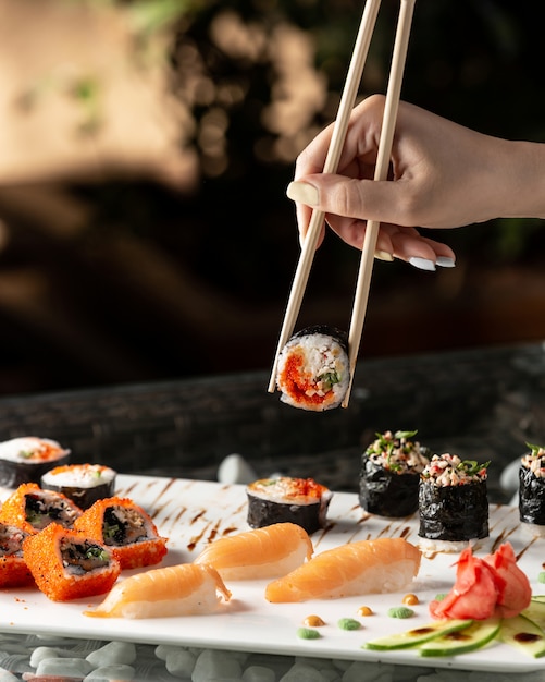 Woman holding sushi roll with chopsticks