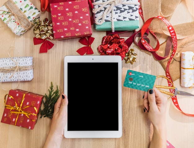 Woman holding tablet and credit card at table 