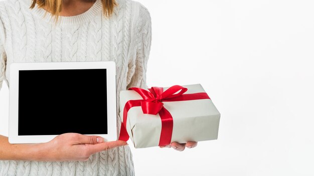 Woman holding tablet and gift box in hands 