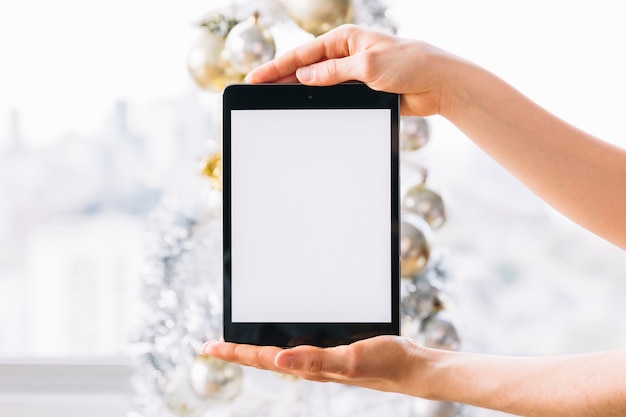 Woman holding tablet near Christmas tree