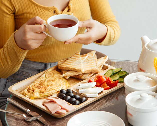 朝食のテーブルでティーカップを保持している女性