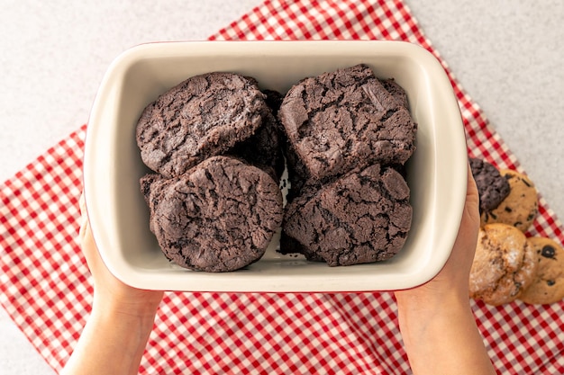 Free photo woman holding tray with chocolate cookies close up