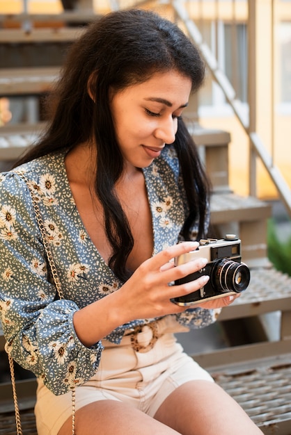 Woman holding a vintage camera and looking at photos