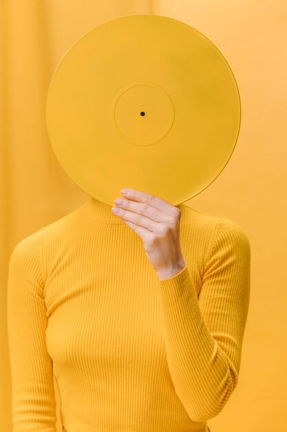 Donna in possesso di vinile davanti al viso in una scena gialla