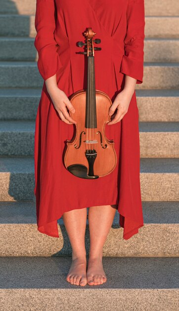 Woman holding violin while posing on steps