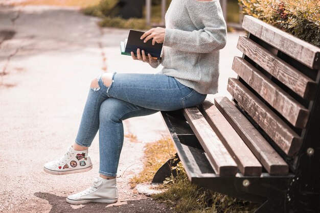 Woman holding volume and sitting on bench