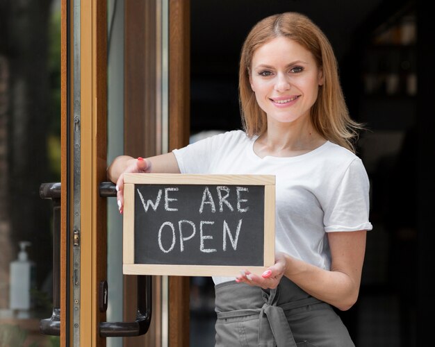 Woman holding we are open sign