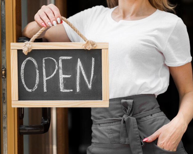 Woman holding we are open sign