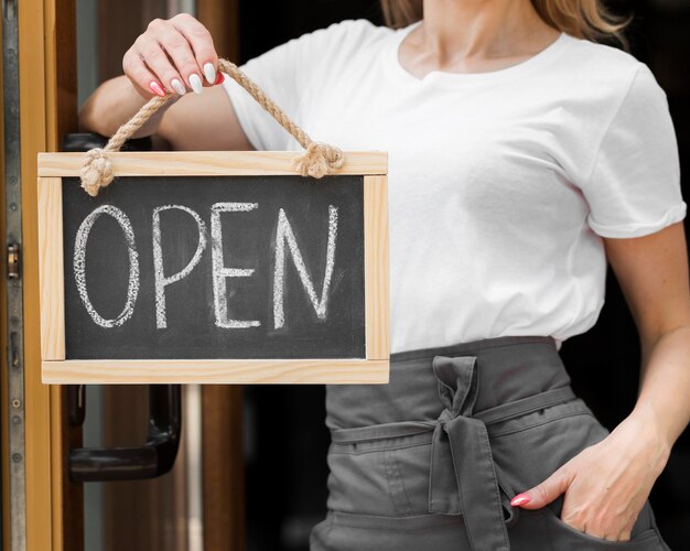 woman holding we are open sign