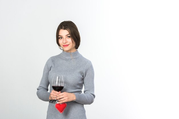 Woman holding wine glass and small heart in hands 