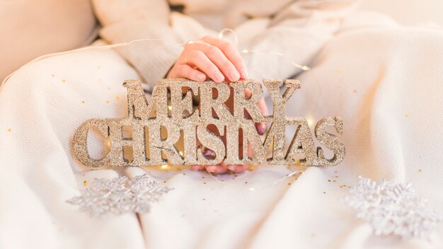 Woman holding wooden Merry Christmas inscription in hands 