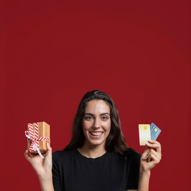 Free photo woman holding a wrapped gift and her credit cards