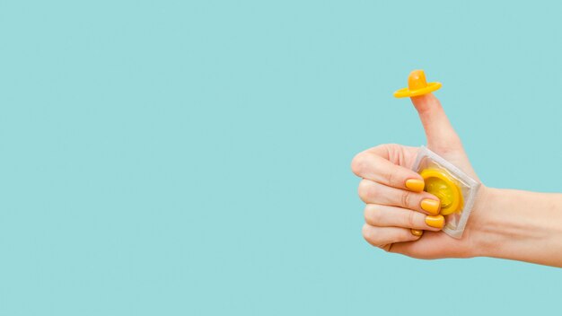 woman holding a yellow condom on her finger