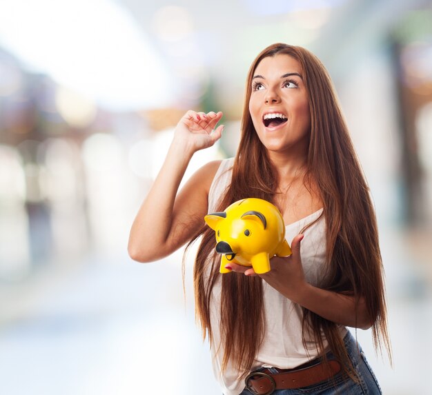 Woman holding yellow piglet moneybox.