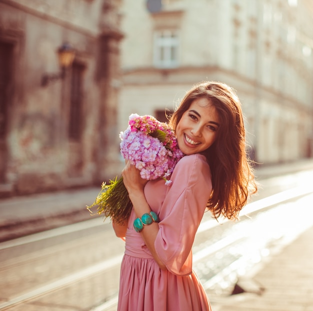 Woman holds bouquet tightly posing on morning street