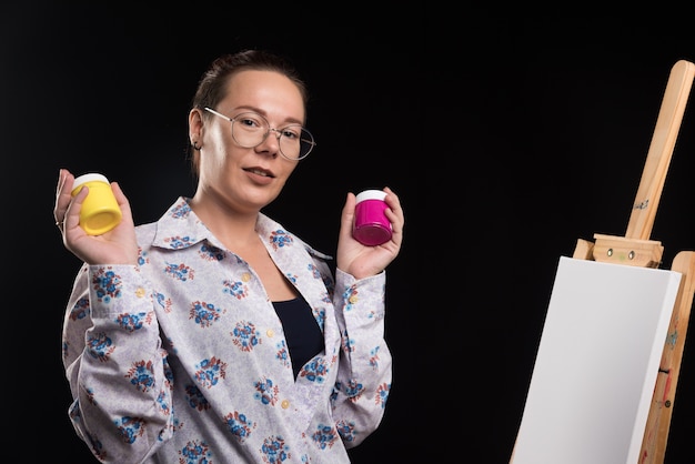 Woman holds brush and paints on black background