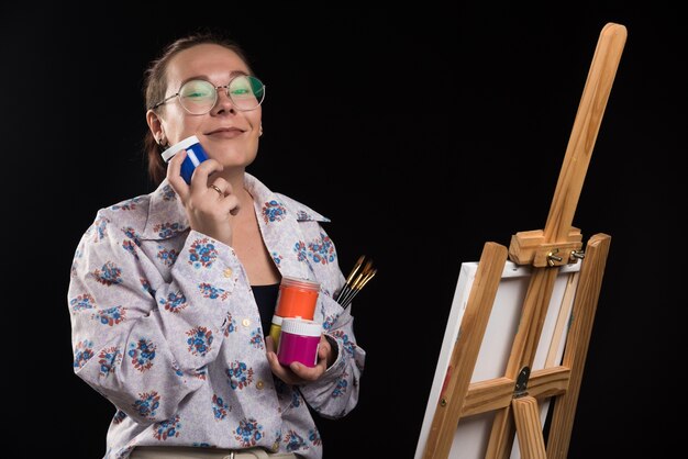 Woman holds brush and paints on black background