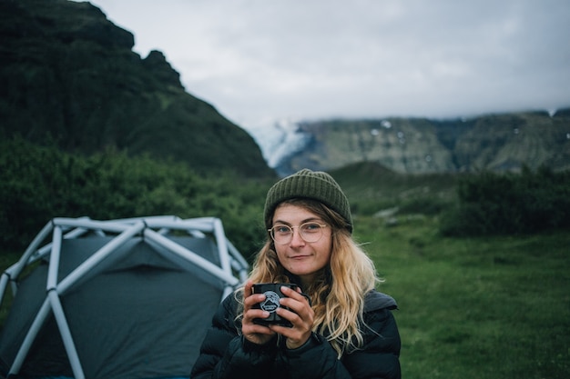 Woman holds camping mug on hike trip in iceland