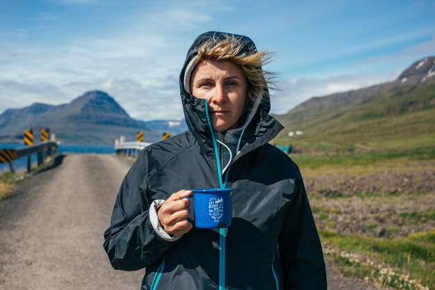 Женщина держит походную кружку во время похода в исландию