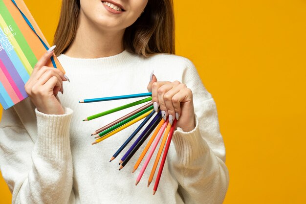 Женщина держит красочные карандаши и красочный блокнот