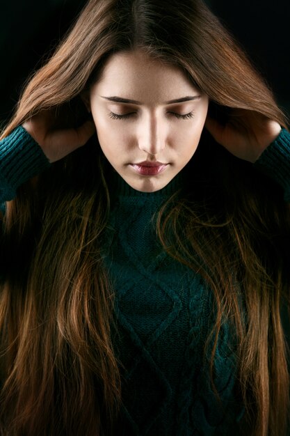 Woman holds her hair up posing in green sweater 