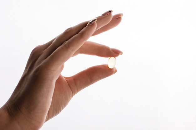 Free photo woman holds in her hand a capsule with vitamins or oil