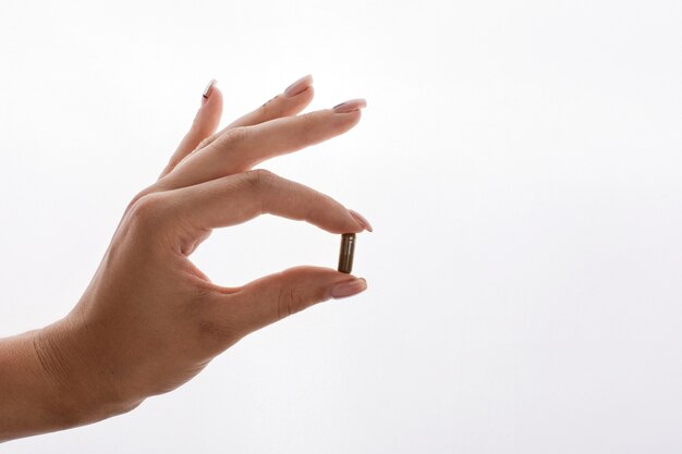 Woman holds in her hand a capsule with vitamins or oil