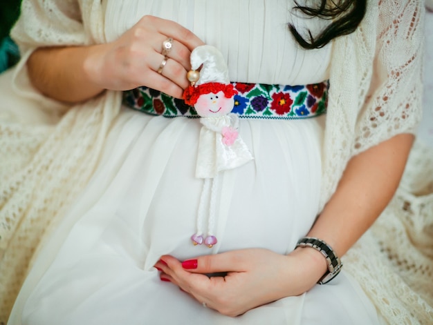 Woman holds little toy on her pregnant belly