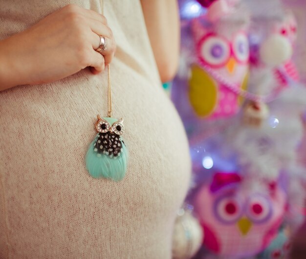 Woman holds little toy owl on her belly