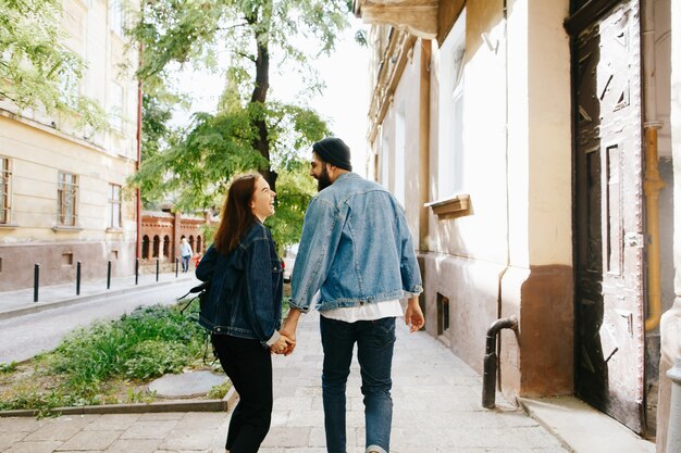 Woman holds man's hand walking with him on the old European city