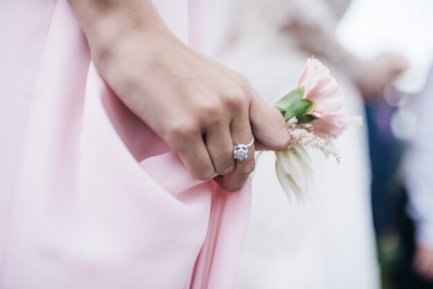 女性は彼女の腕の中にピンクboutonniereを保持する