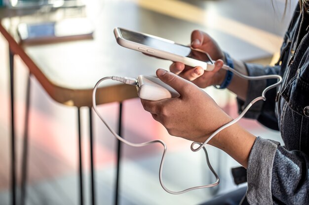 A woman holds a power bank and a phone in her hands