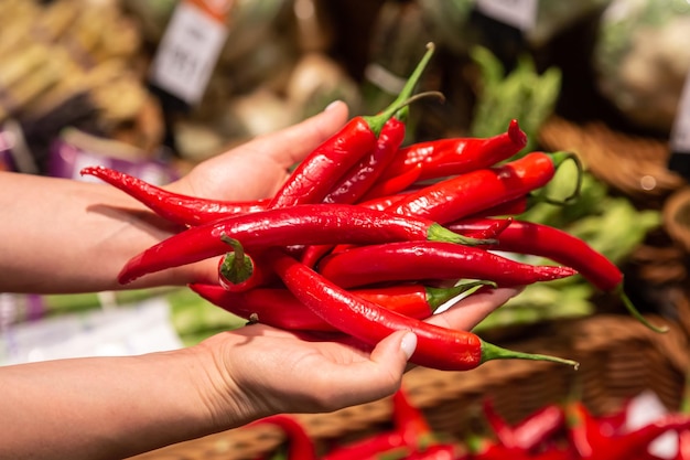 Foto gratuita la donna tiene il peperoncino rosso nel negozio o nel mercato da vicino