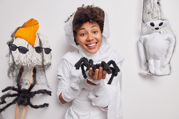  woman holds spider makes magic trick smiles happily develops imagination wrapped in white fabric poses indoor. Fantasy and creativity. Its too cute to spook