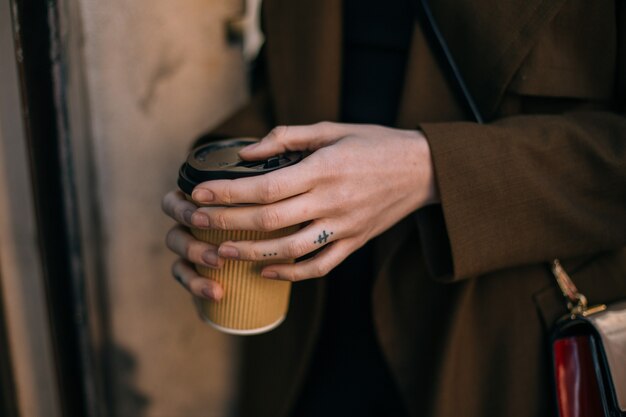 Free photo woman holds take away to go coffee cup on street