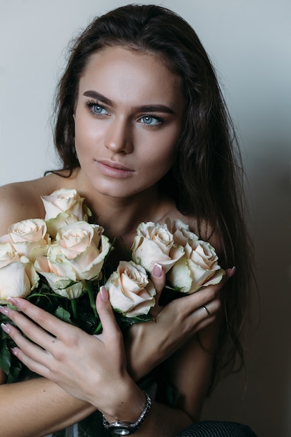 Woman holds white roses before her chest