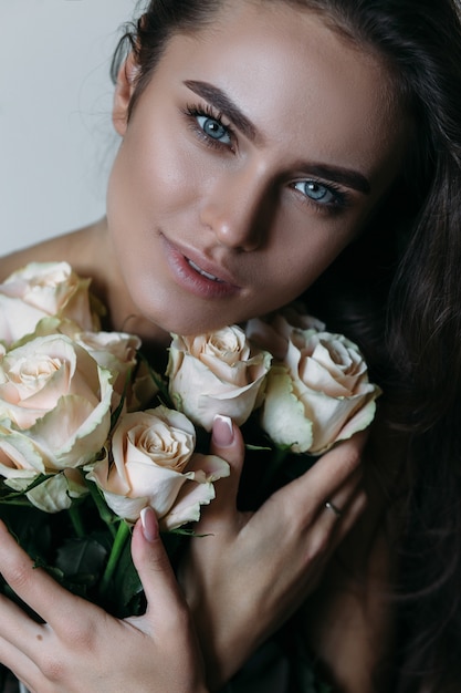 Free photo woman holds white roses before her chest