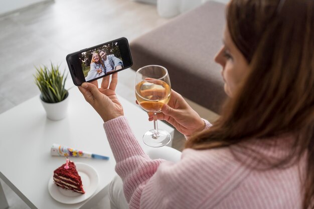 Woman at home in quarantine having a drink with friend over smartphone