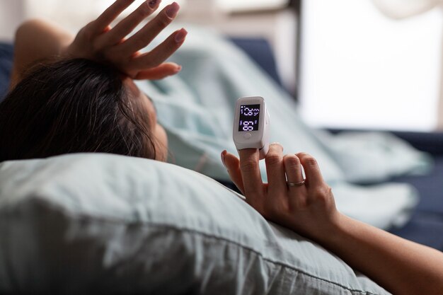 Woman at home using medical oximeter equipment to measure oxygen saturation