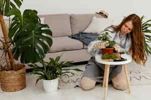 Free photo woman at home with pot of plant and gardening tool