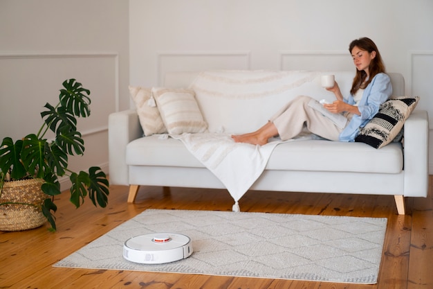 Free photo woman at home with robotic wireless vacuum cleaner