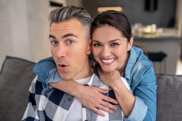 Woman hugging cheerful man looking at camera