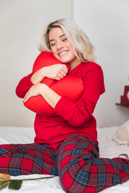 Free photo woman hugging heart pillow on valentines day