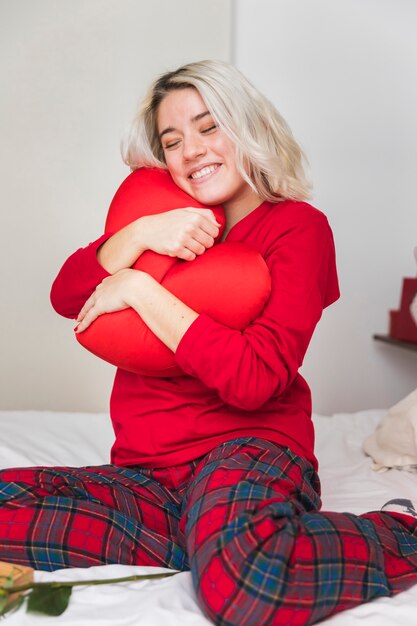 Woman hugging heart pillow on valentines day