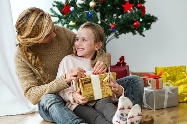 황금 선물 및 선물 배경으로 그녀의 딸을 포옹하는 여자