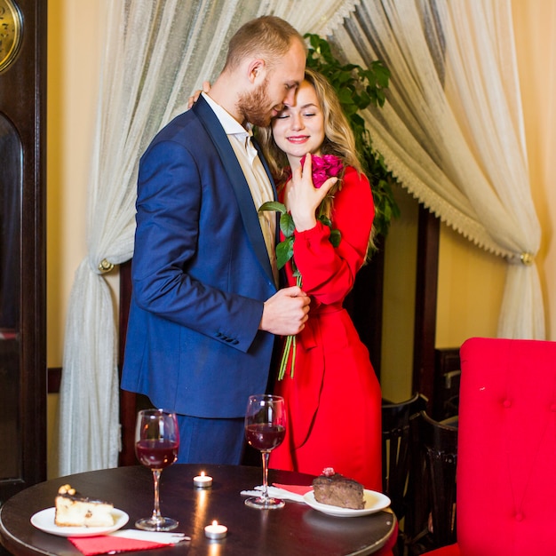 Free photo woman hugging man with roses in restaurant