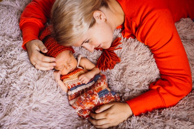 Женщина обнимает новорожденного, лежащего на розовом одеяле