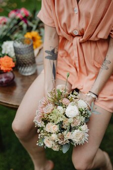 Женщина в оранжевом комбинезоне с букетом цветов